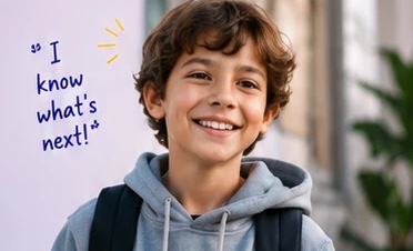A smiling boy with a backpack, with the handwritten note “I know what's next!”